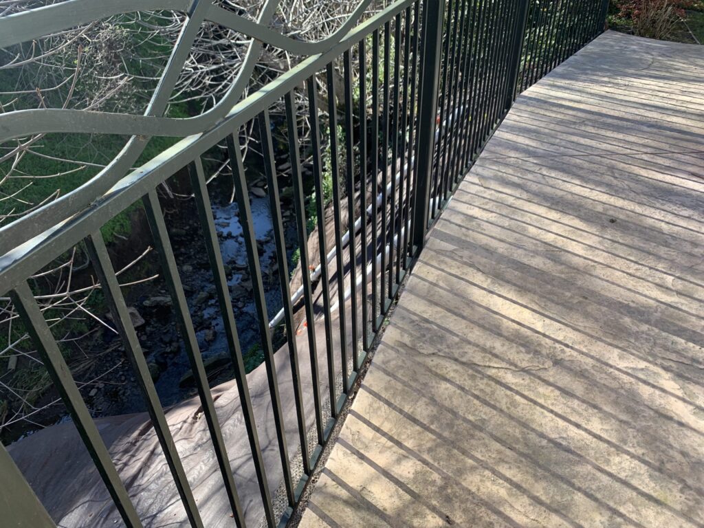 Completed Project This v The 20 foot area extending down to the creek bed beneath the ornamental iron guardrail has been armored with a tarp to prevent future erosion problems scaled